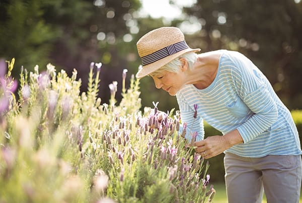 A senior woman smelling flowers while gardening
